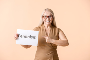Fototapeta na wymiar Woman holding paper with word FEMINISM on color background