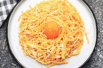 Plate with tasty pasta, cheese and egg on grey background