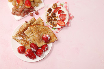 Pancakes with strawberries and granola, granola on a pink sunny background. The concept of healthy and natural food. Healthy breakfast, food for children. selective focus., flat lay Shrovetide.