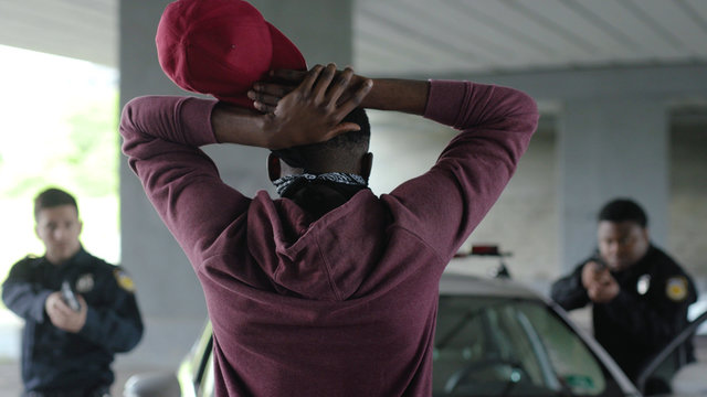 Shot back african american offender in mask stand hands up in patrol car in handcuffs burglar crime hold danger gangster gun robber handgun illegal law outlaw arrest bad guy close up slow motion