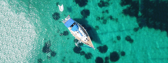 Aerial drone ultra wide photo of sail boat docked in tropical exotic bay with emerald coral reef