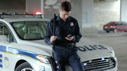 Policeman cops stand near patrol car use phone accepting emergence call enforcement talk officer...