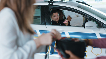 Young two policemen eating donut smile talk see how a man steals a woman's bag near patrol car help...