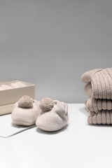 Baby booties, sweaters and socks made of natural beige fabrics lie on the table