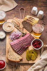 Sliced Deli Pastrami on wooden board, flat lay