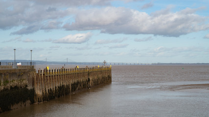 Fototapeta na wymiar A view of the Severn Estuary near Bristol, England UK with the new road bridge in the distance and Portishead pier in the foreground.