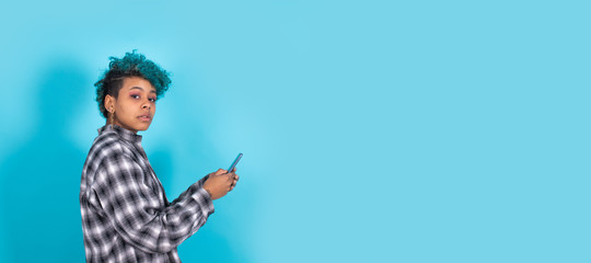 african american girl or woman with mobile phone or smartphone isolated on blue background