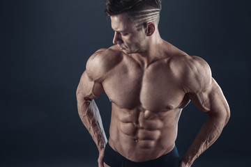 Fototapeta na wymiar Strong Athletic Sexy Muscular Man on Black Background.