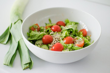 Bowl with salad and fresh vegetables on kitchen table. Healthy food