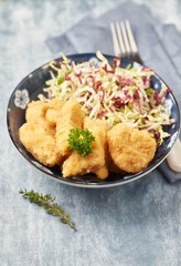 Chicken nuggets with raw salad on bright wooden background.	