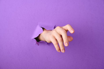 Hand is thrust through a hole in the paper background