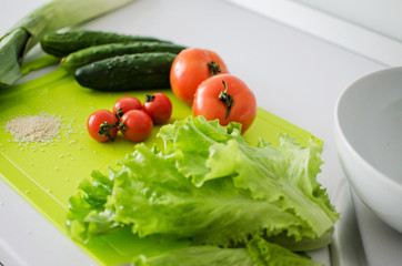 Bowl with salad and fresh vegetables on kitchen table. Healthy food