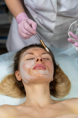 Beautician makes a procedure for a girl to improve facial skin condition
