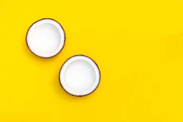 Coconut halves on bright yellow background. Top view with copy space