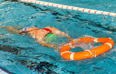 socorrista entrenando en una piscina con un flotador salvavidas