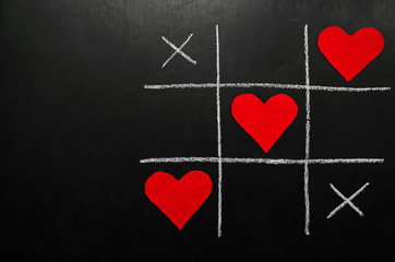 lovers day concept. tic-tac-toe game where instead of zeroes are red hearts. on a black background....