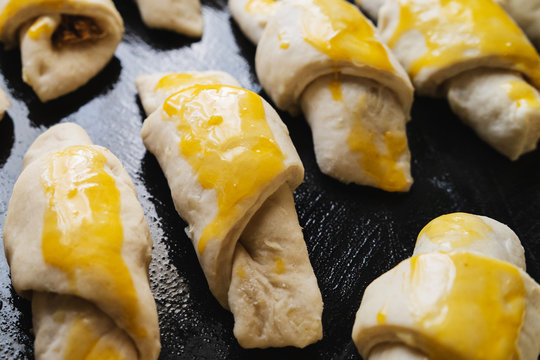 Raw serbian kifla cheese crescent rolls egg glazed homemade ready to bake high angle view on black casserole dish close up