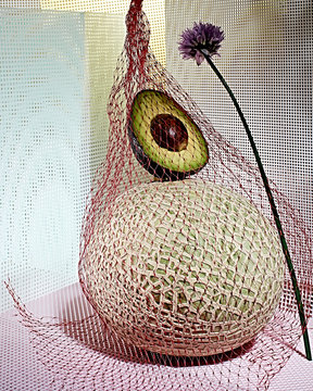 Melon and halved avocado in mesh bag with garlic flower