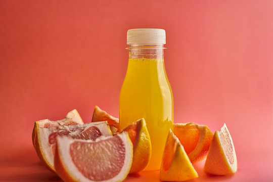 Orange Juice Bottle On Orange Background With Segments Of Pink Oranges, Horizontal