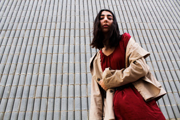 Cristina in her dress and her jacket brown in fron of a striped wall.