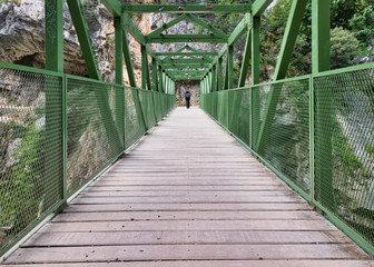 Woman crossing a metallic bridge during a hiking holiday in northern Spain