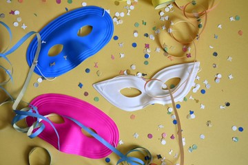carnival masks with confetti and streamers on a yellow background