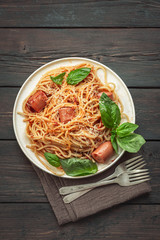Traditional Italian spaghetti pasta with sausages and basil leaves top view.