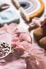 Many different baby textile stuff on a wooden background with toys and pink dress