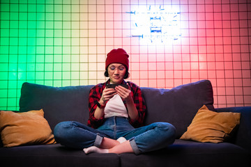 Pretty young woman using mobile phone playing online game at home