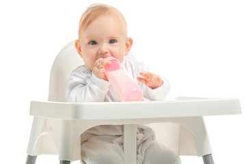 Baby with bottle of milk sitting in high-chair on white background