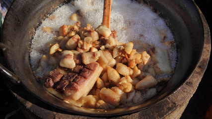 Pork greaves preparing in a big pot, tasty snacks in hot fat made from bacon