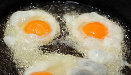 Eggs preparing in a frying pan, boiling oil or fat