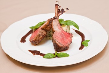 Grilled veal ribs meat with garnish, mint leaves and spicy tomato sauce, served on white ceramic plate, shallow dof food menu design