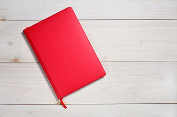 Red notebook on a white wooden background