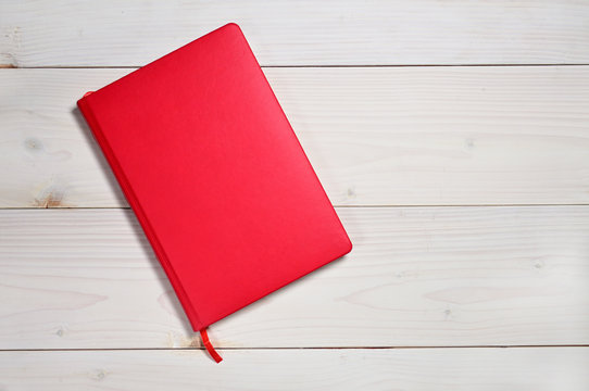 Red notebook on a white wooden background