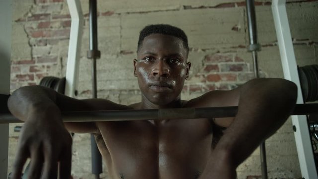 Shirtless African American Man Looking Into Camera While Resting At The Squat Rack