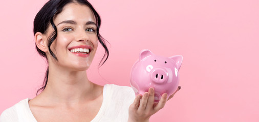 Young woman with a piggy bank on a pink background