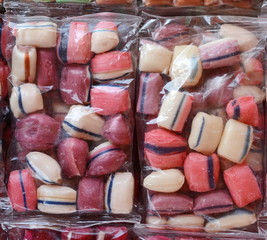 Tasty candies in plastic bag as a background.