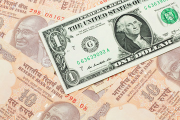 A close up image of a an American one dollar bank note with Indian ten rupee bank notes in macro