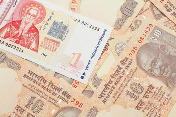 A macro image of a red and white Bulgarian lev bank note with Indian ten rupee bank notes