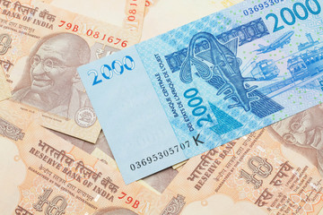 A close up image of a blue, two thousand, West African franc bank note in macro on a background of United States one dollar bills