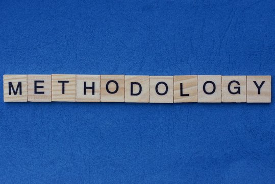 gray word methodology from small wooden letters on a blue table