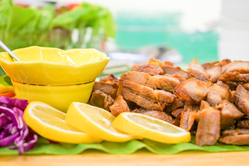 Roasted slided pork in Asia Thai style with specific local sauce style and vegetable cucumber, green oak, red peper, mint slided lemen on wood plate.