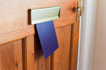 Blank leaflet or flyer being posted through a letter box unwanted junk mail