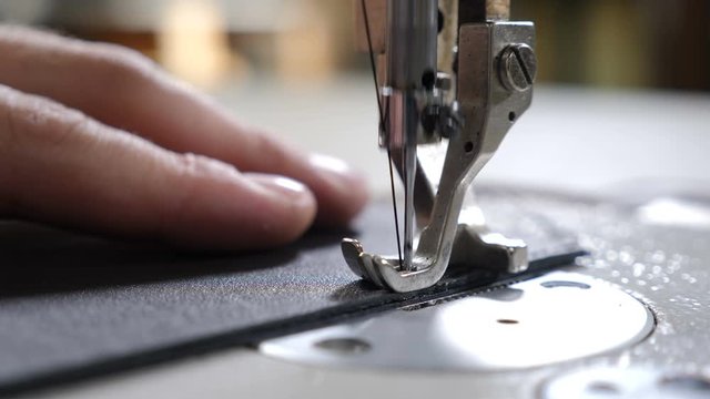 Craft man at work. workshop of making leather bag - craftsman stitches the pouch on sewing machine close-up. Item of clothing or bag. sewing in phase of overstitching. Tailoring Process. 4k video