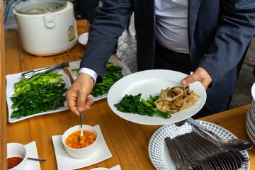 business man in business suit preparing the Fried noodle with pork and broccoli for lunch.