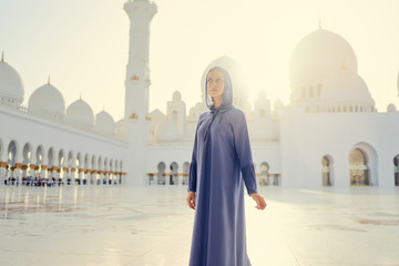 Traveling by Unated Arabic Emirates. Woman in traditional abaya standing in the Sheikh Zayed Grand Mosque, famous Abu Dhabi sightseeing.