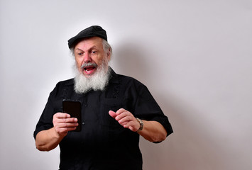 Old man looking at his cellphone with a shocked expression.