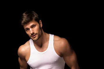 Muscle strong beautiful stripped male model with white shirt in denim gray jeans on black isolated font background © Oleh Phoenix