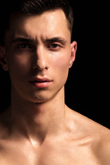 Handsome wet sport sexy stripped guy portrait with waterdrops and smoke on isolated black background